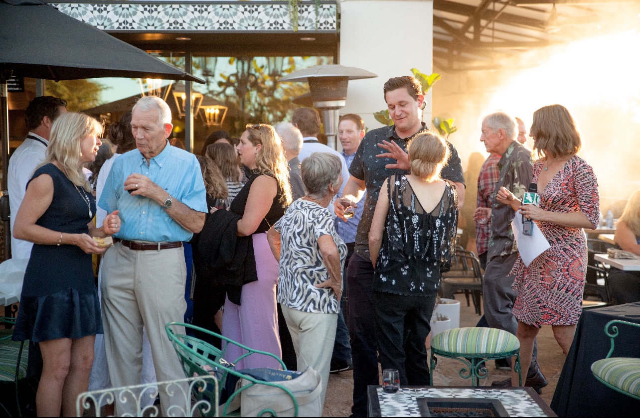 Guests in conversation on a sunlit outdoor terrace